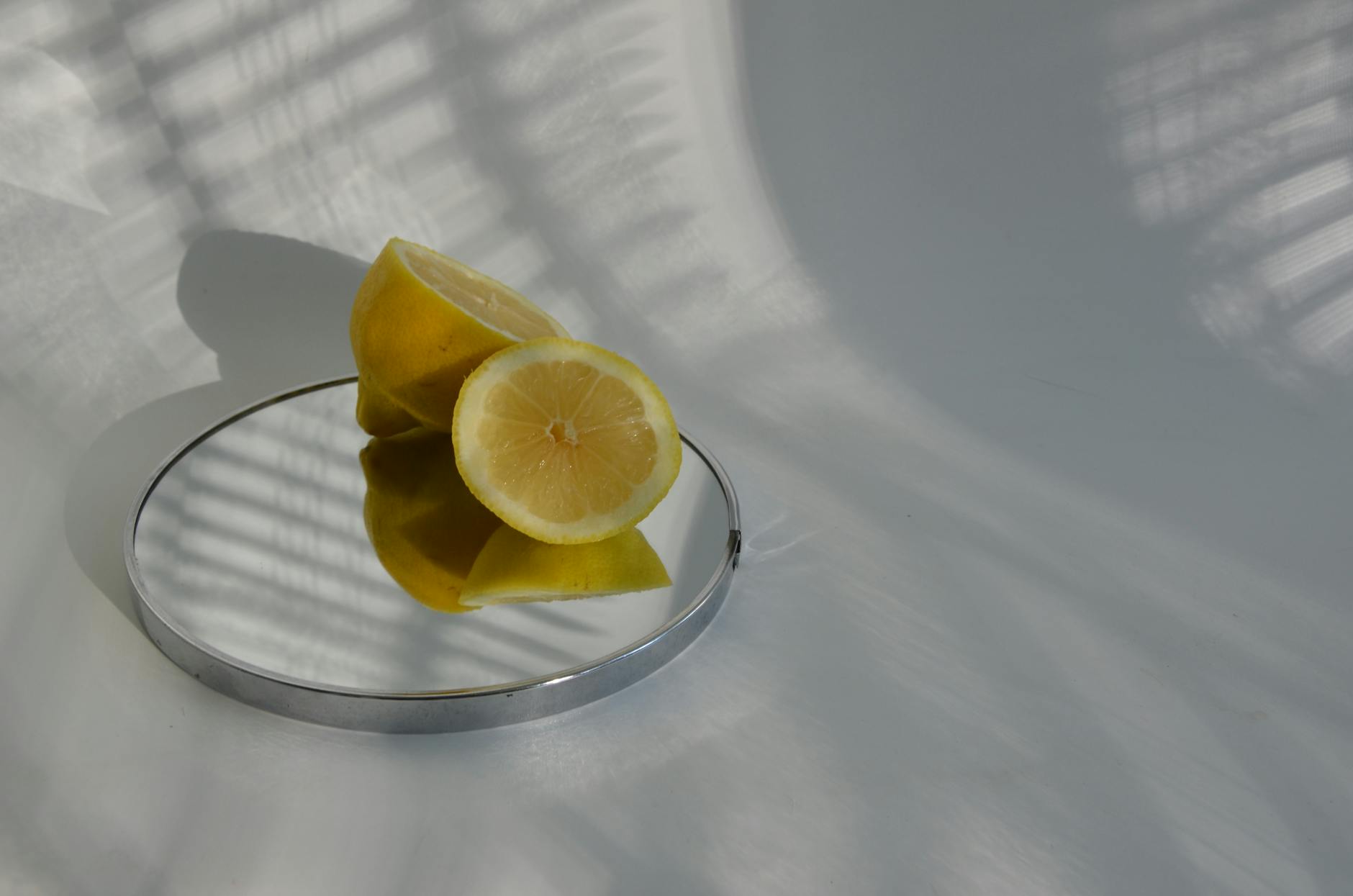 Hand holding a fresh lemon on a soft pink background with additional lemons nearby