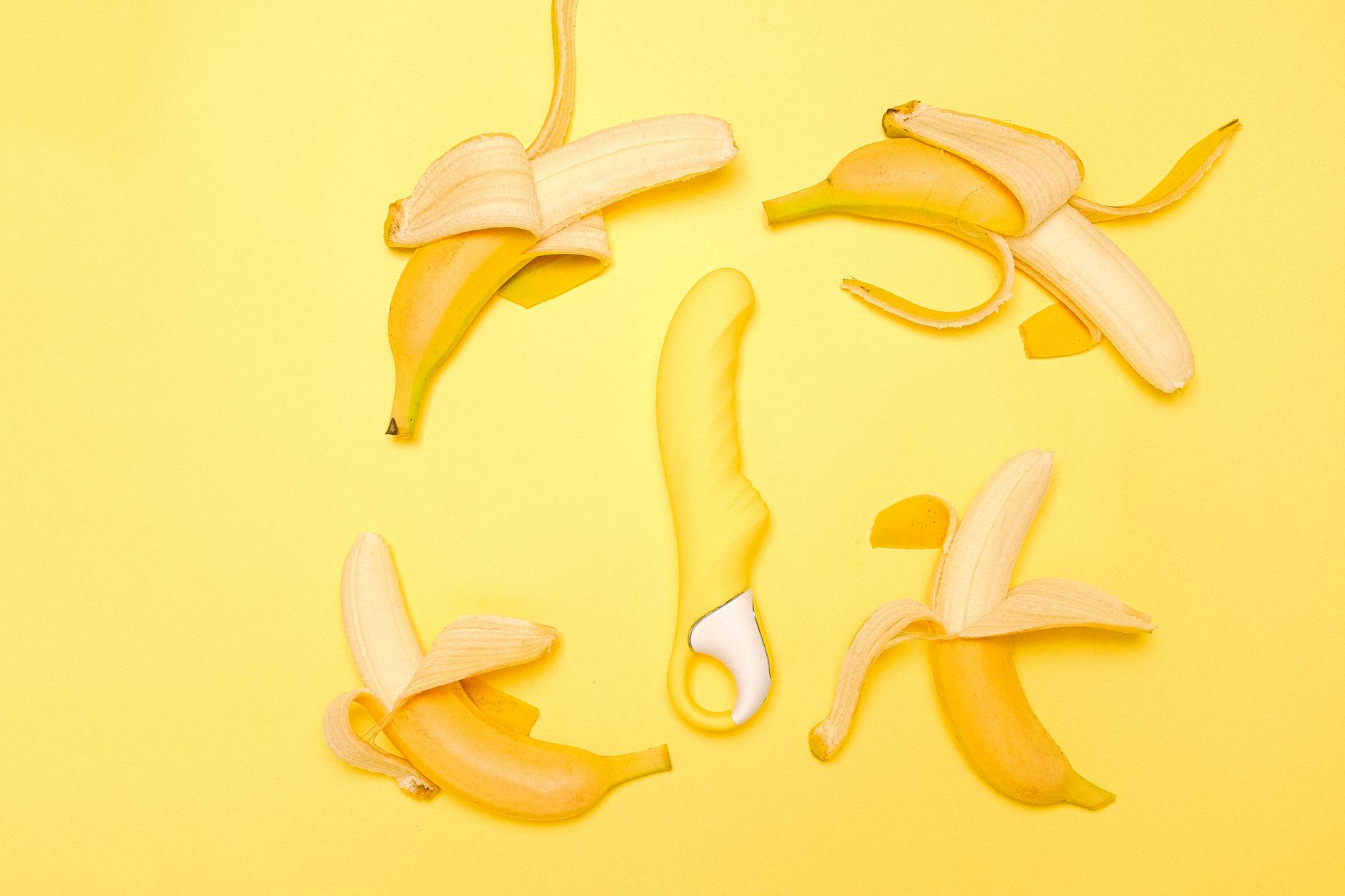 A yellow lemon vibrator on a bright yellow background with fresh citrus elements