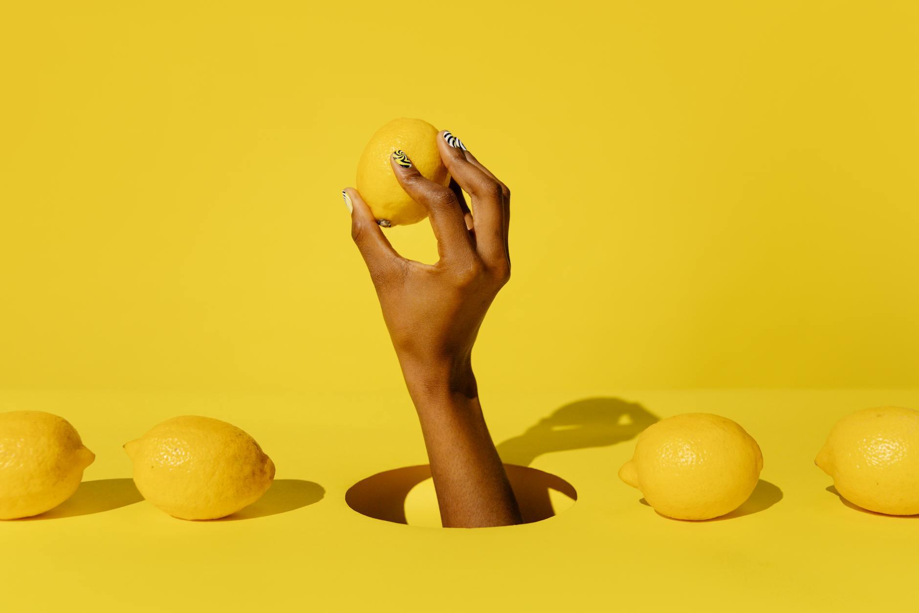 Hand holding a fresh lemon against a vivid yellow background, symbolizing renewed vitality and reconnection