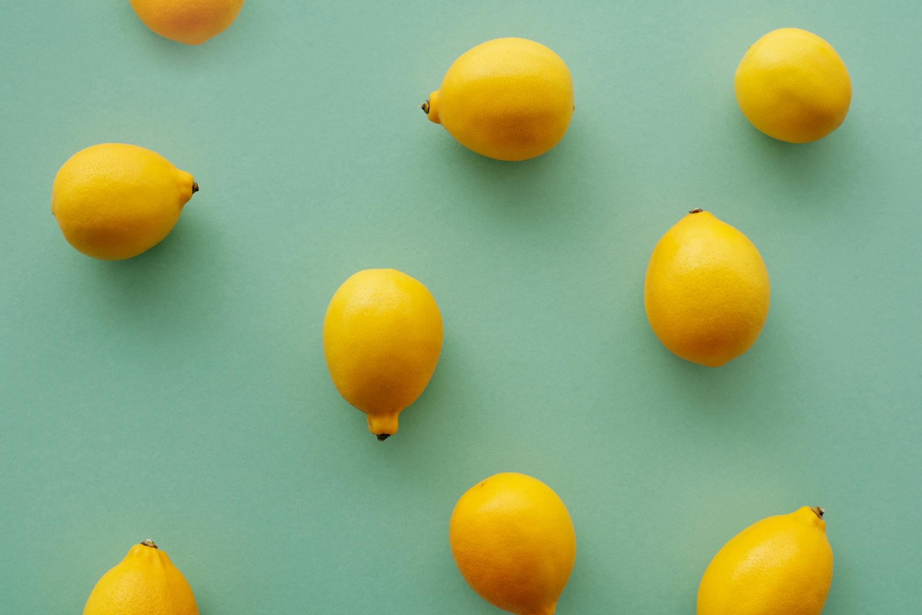 Bright yellow lemons arranged on a pastel green background symbolizing renewed sensation and vitality