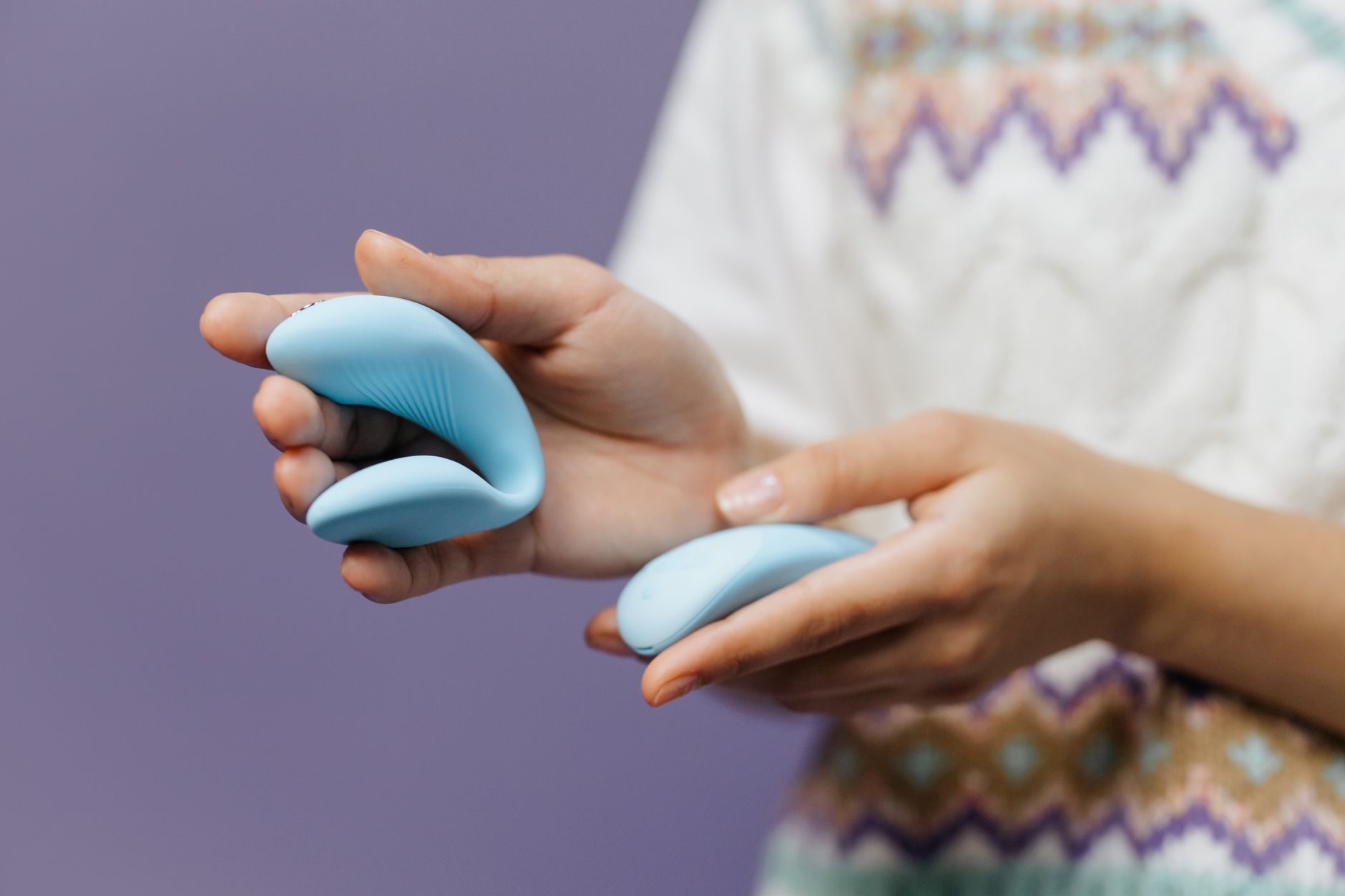 Intimate close-up of hands holding a sleek vibrator together during partnered intimacy.