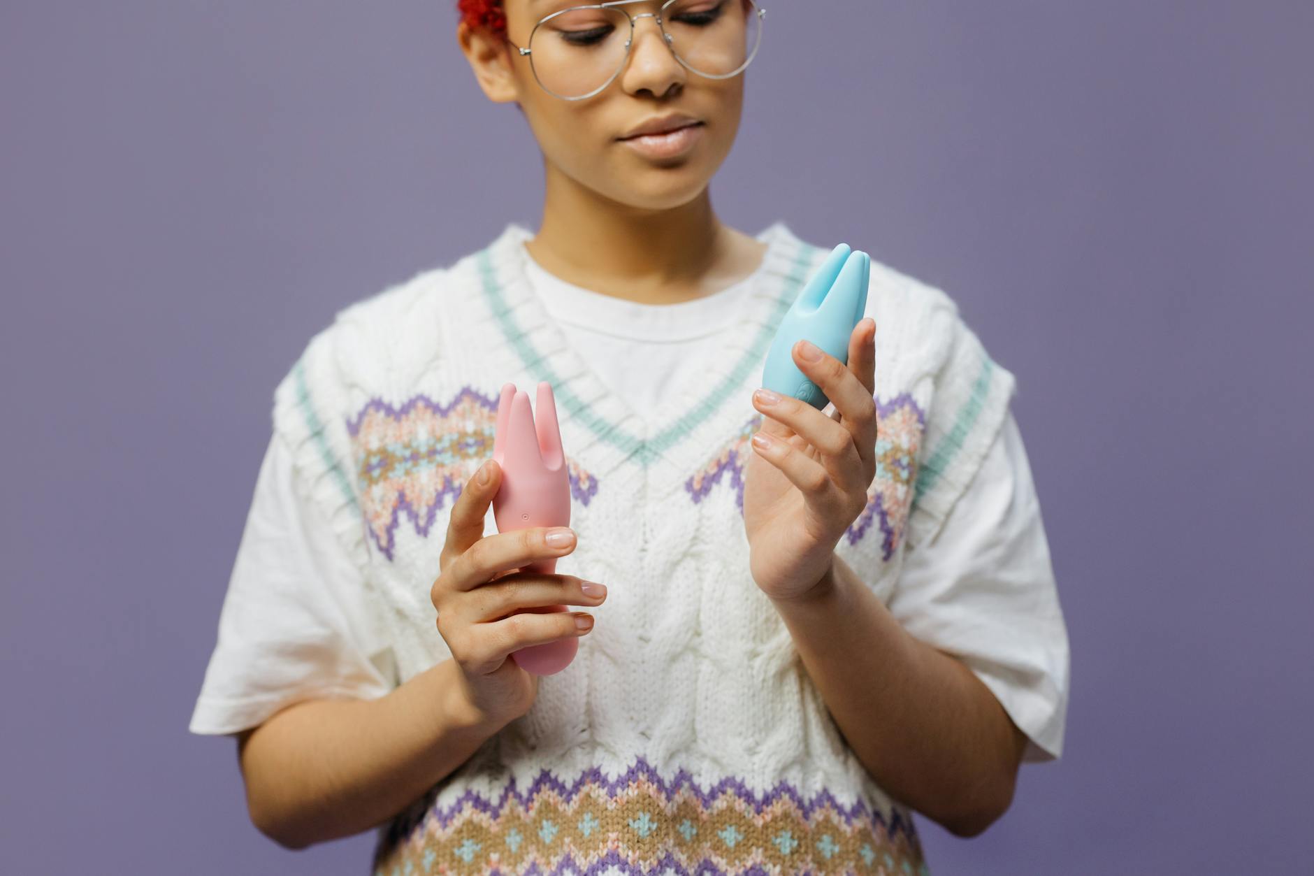 Close-up of hands holding a sleek lemon vibrator against a purple background