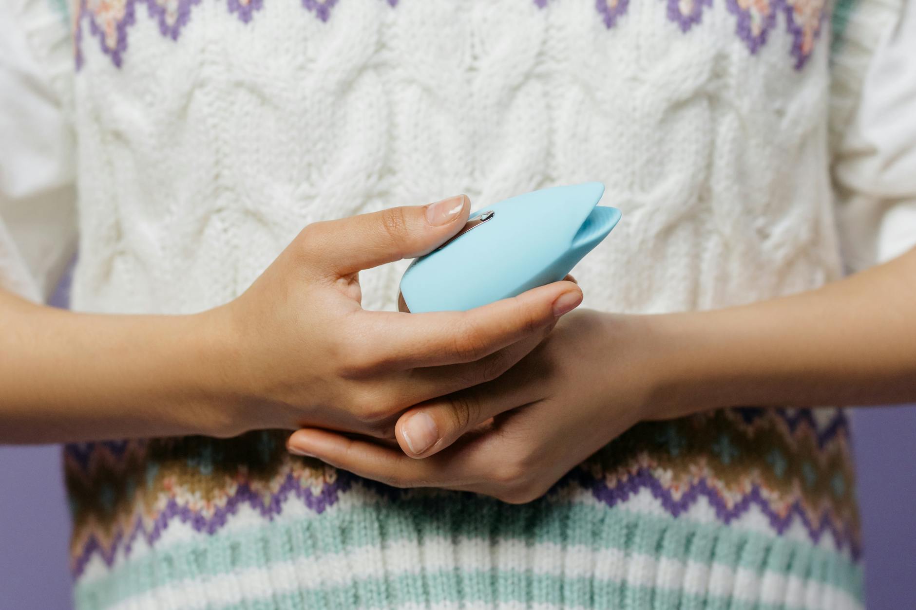 Close-up of hands holding a blue personal massager, representing reclaiming pleasure without shame