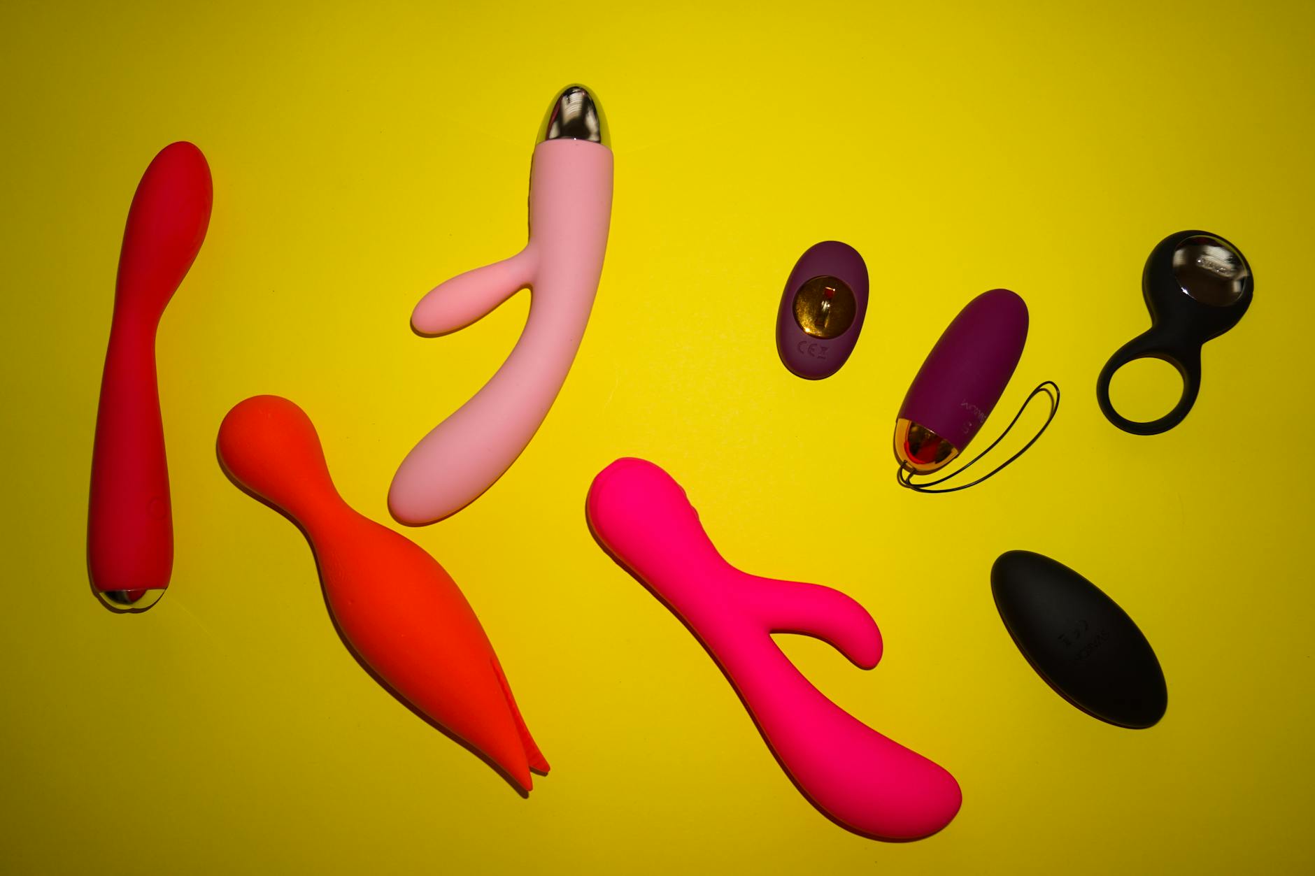 Colorful sex toys on a bright yellow background, showcasing various clitoral vibrators and intimate wellness tools.