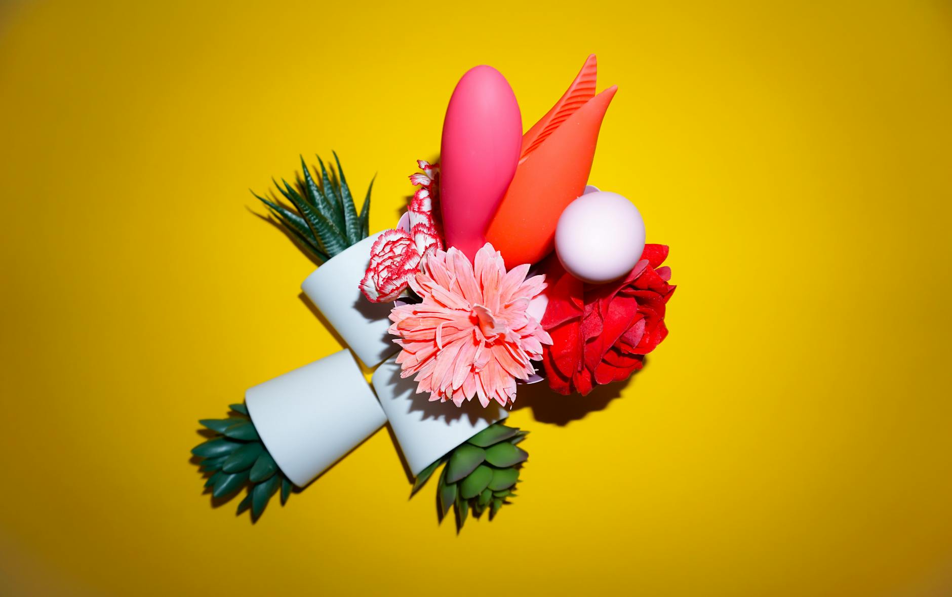 Composizione colorata di fiori e oggetti astratti su uno sfondo giallo luminoso.