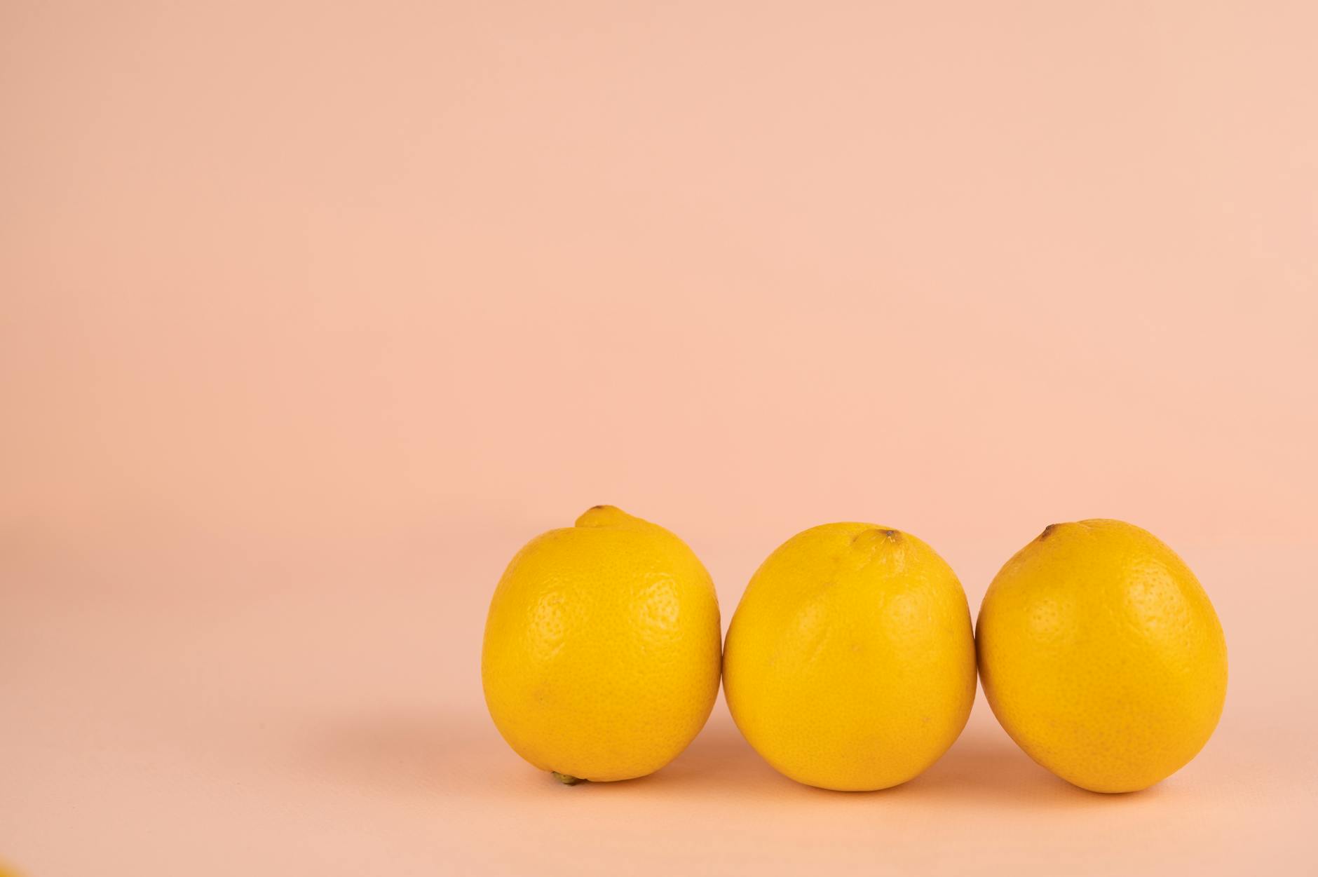 Bright yellow lemons arranged on a pastel background, evoking freshness and gentle sensation